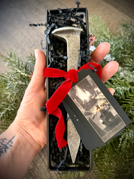 Hand holding a blacksmithing class voucher gift box for knife making experiences