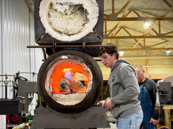 Student forging railroad spike knife blade at Heritage Designs blacksmithing class